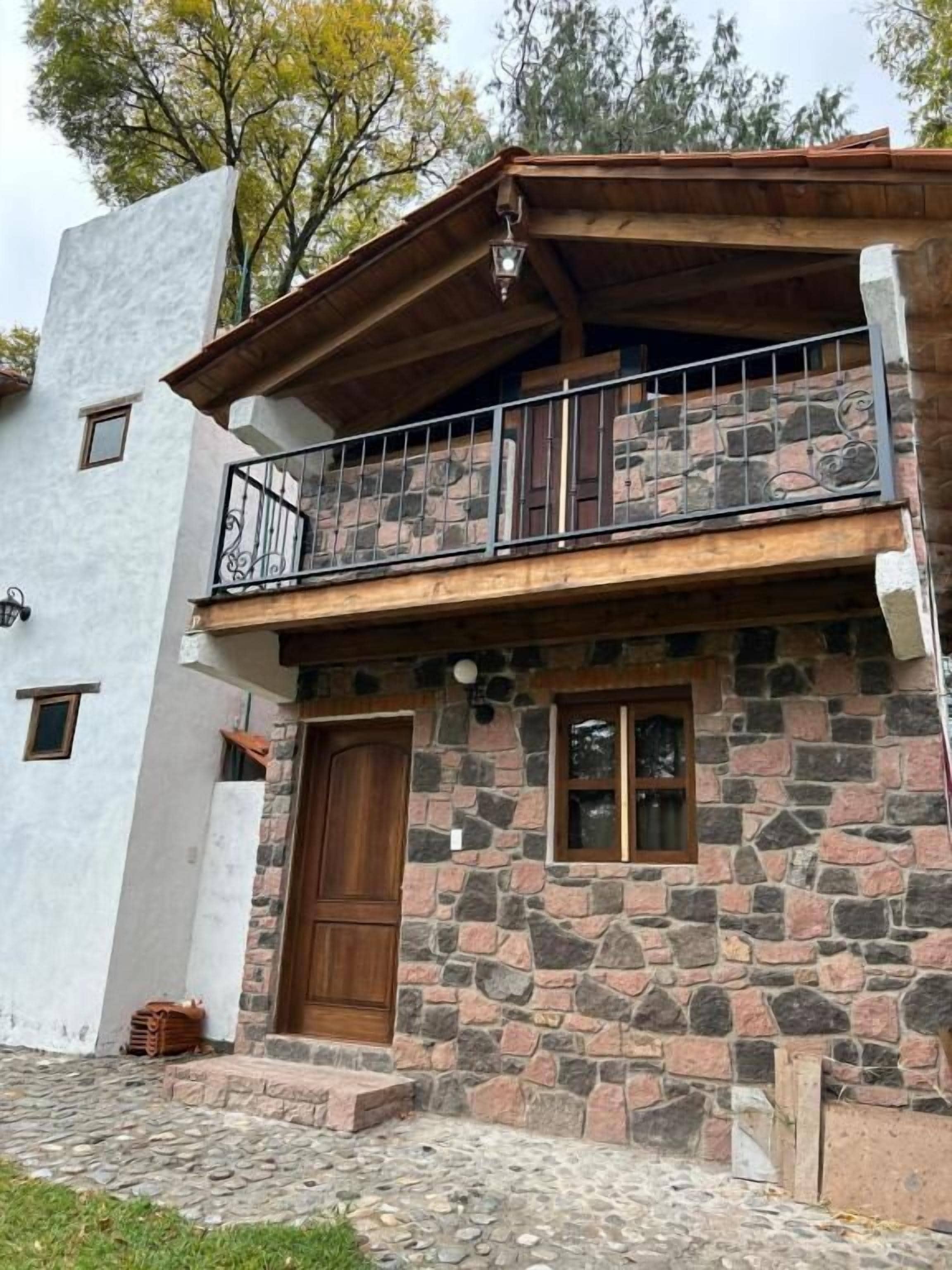 Un edificio de dos pisos de piedra con un balcón y una puerta de madera.