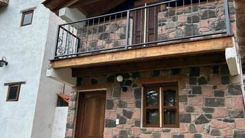Un edificio de dos pisos de piedra con un balcón y una puerta de madera.
