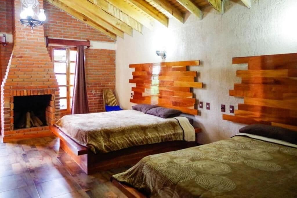 Una habitación con dos camas, una chimenea de ladrillo y vigas de madera en el techo.