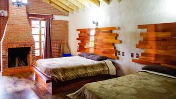 Una habitación con dos camas, una chimenea de ladrillo y vigas de madera en el techo.