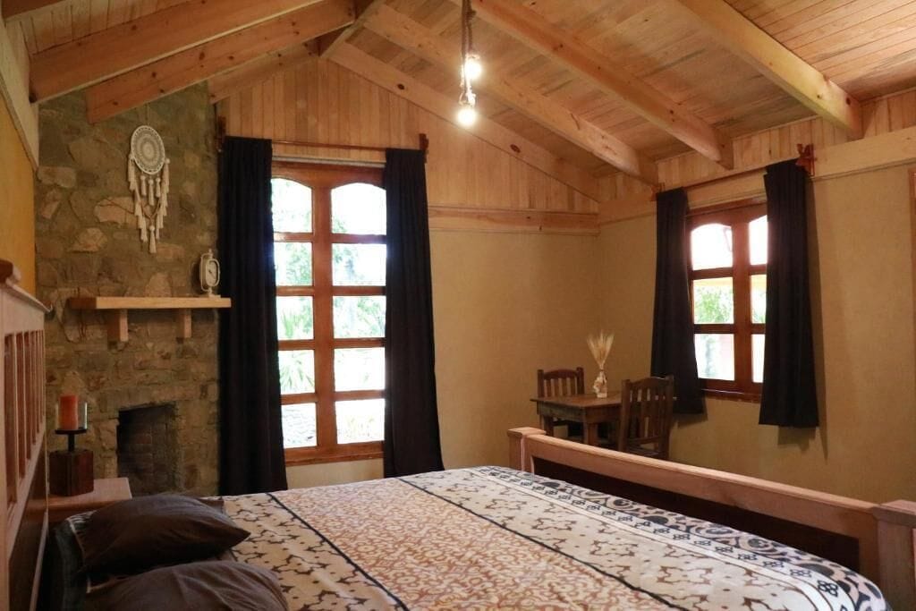 A room with a bed, a fireplace, and two windows with curtains.