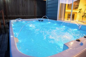 A hot tub with a wooden deck and a window with a plant. - Restful Bana Resort (Marysville)