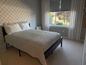 A bedroom with a bed, a window with curtains, and patterned wallpaper. - Restful Bana Resort (Marysville)