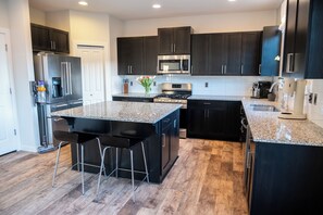 A modern kitchen with dark cabinetry, stainless steel appliances, and a granite countertop. - Restful Bana Resort (Marysville)