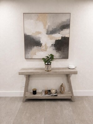 A minimalist console table with a geometric-patterned vase, a small plant, and a decorative object. - Bright, stylish 3BR/2BA pet-friendly retreat near Wynwood, Design District & MIA (Miami)
