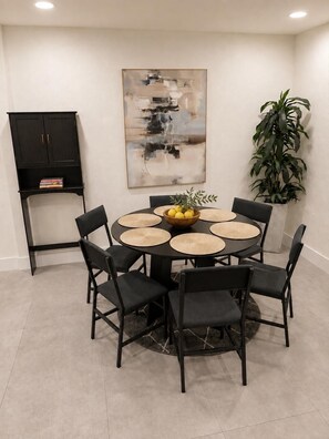 A dining area with a round table, black chairs, and a potted plant. - Bright, stylish 3BR/2BA pet-friendly retreat near Wynwood, Design District & MIA (Miami)