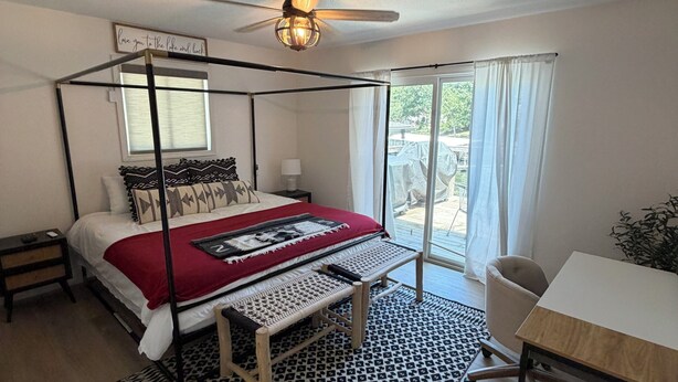 Un lit à baldaquin avec une couverture rouge, un bureau avec une chaise et une fenêtre avec des rideaux.