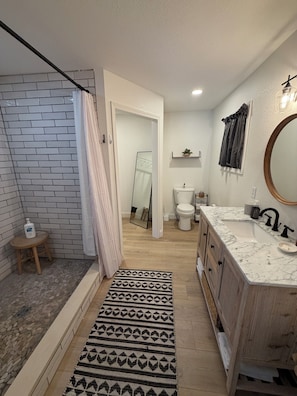 A modern bathroom with a marble sink, wooden vanity, and a large mirror. - Updated Lakefront Home in quiet cove makes the perfect swimming spot with a dock (Sunrise Beach)