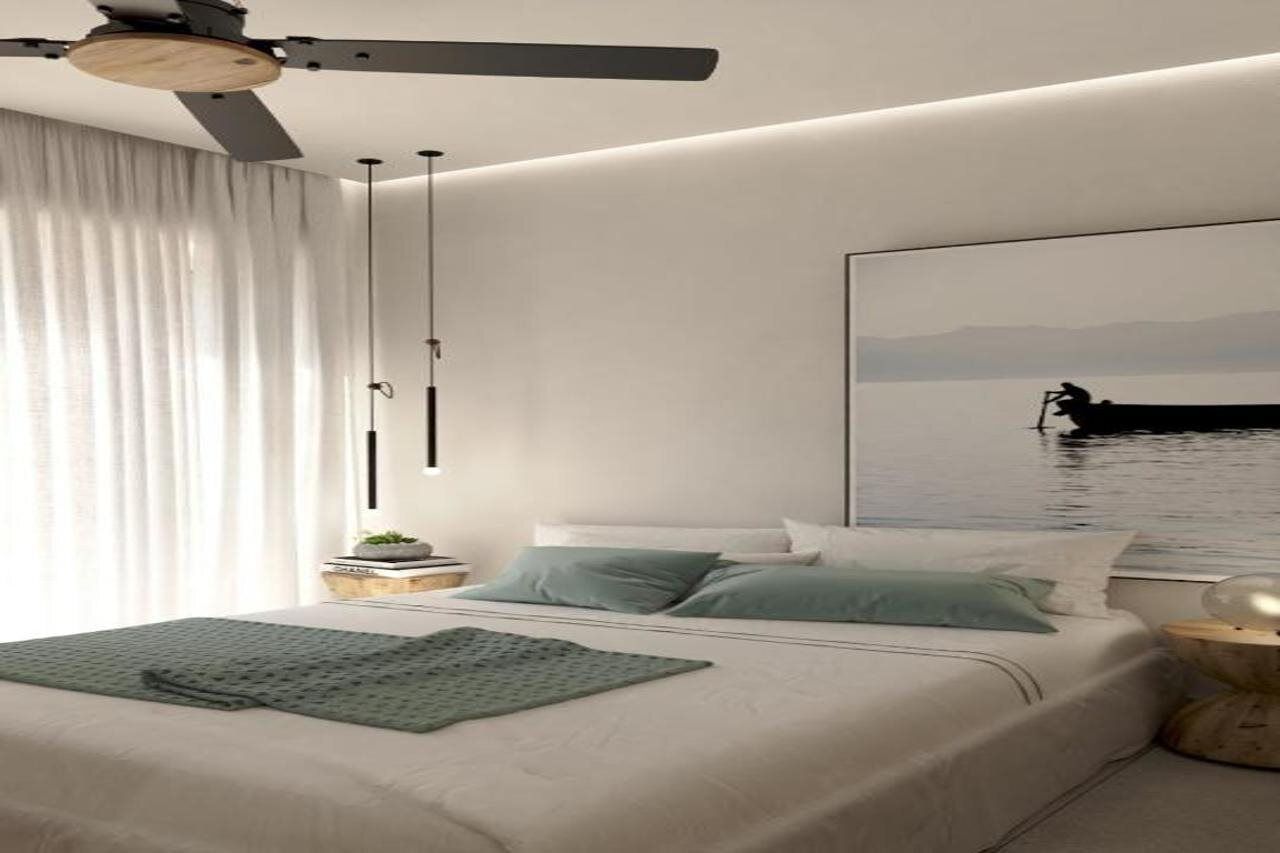 Ein Schlafzimmer mit einem Bett, einem Deckenventilator, einem Fenster mit Vorhängen, einem Nachttisch mit Lampe und einem großen gerahmten Bild an der Wand.
