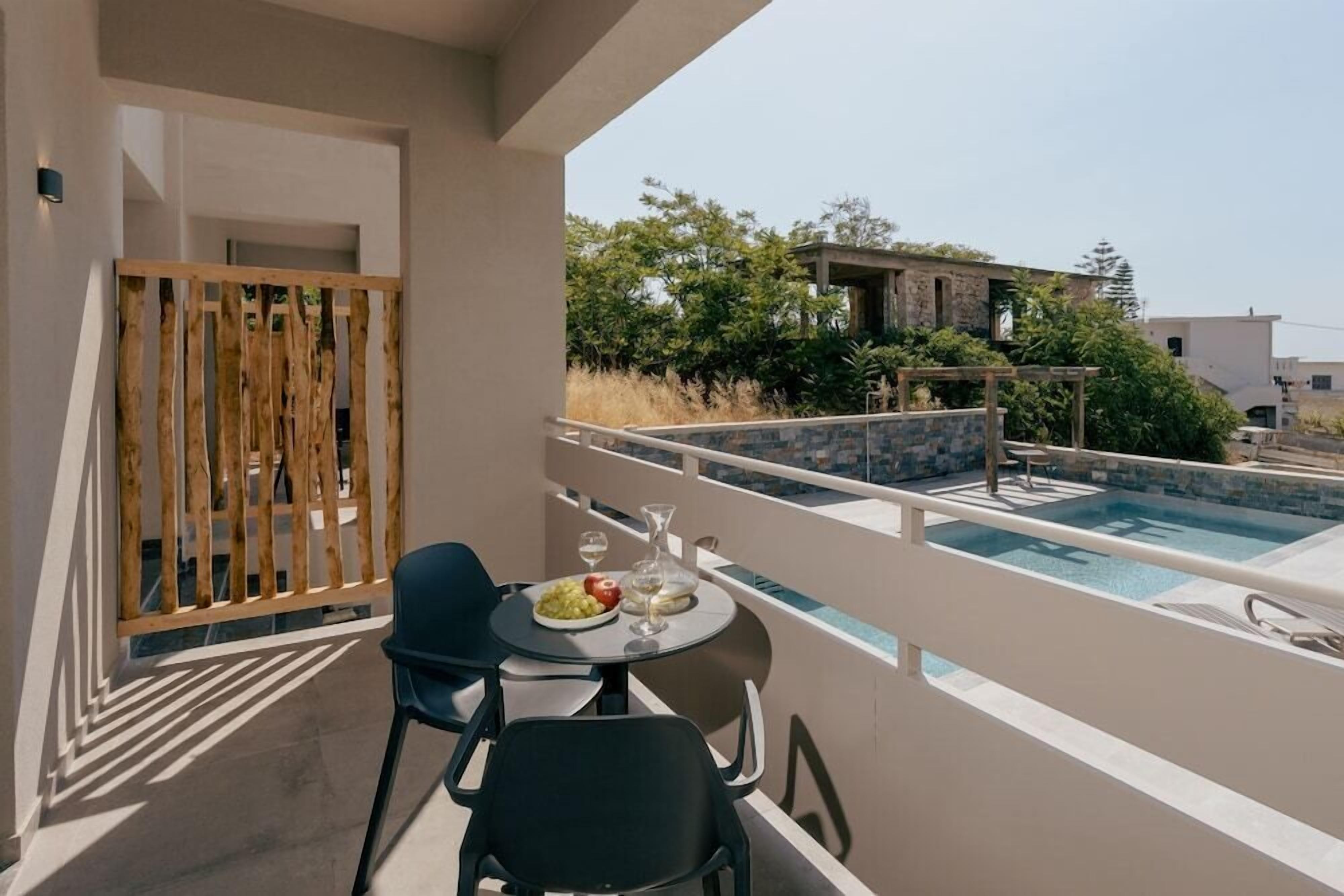 Un balcon avec une piscine, une table avec une assiette de nourriture et des chaises.