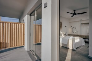Un dormitorio moderno con cama, ventilador de techo y vistas a través de un ventanal.