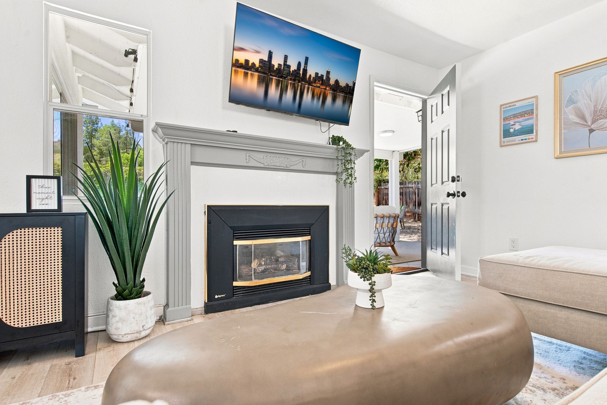 A living room with a fireplace, a large painting, and a view of the outdoors.