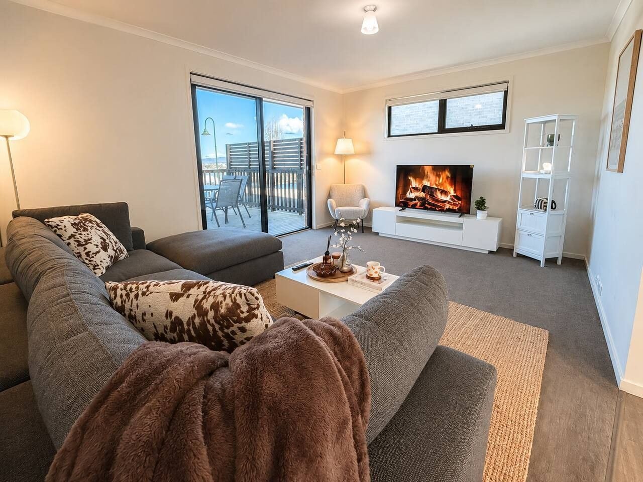 A living room with a sofa, a coffee table, a TV, and a fireplace.