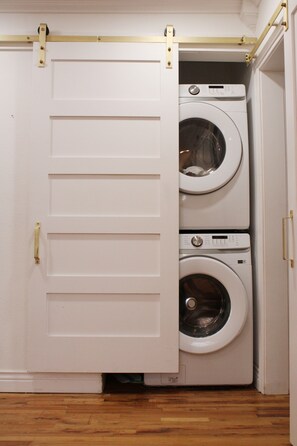 Una sala de bugaderia amb dues rentadores superposades i una porta amb mànega daurada.