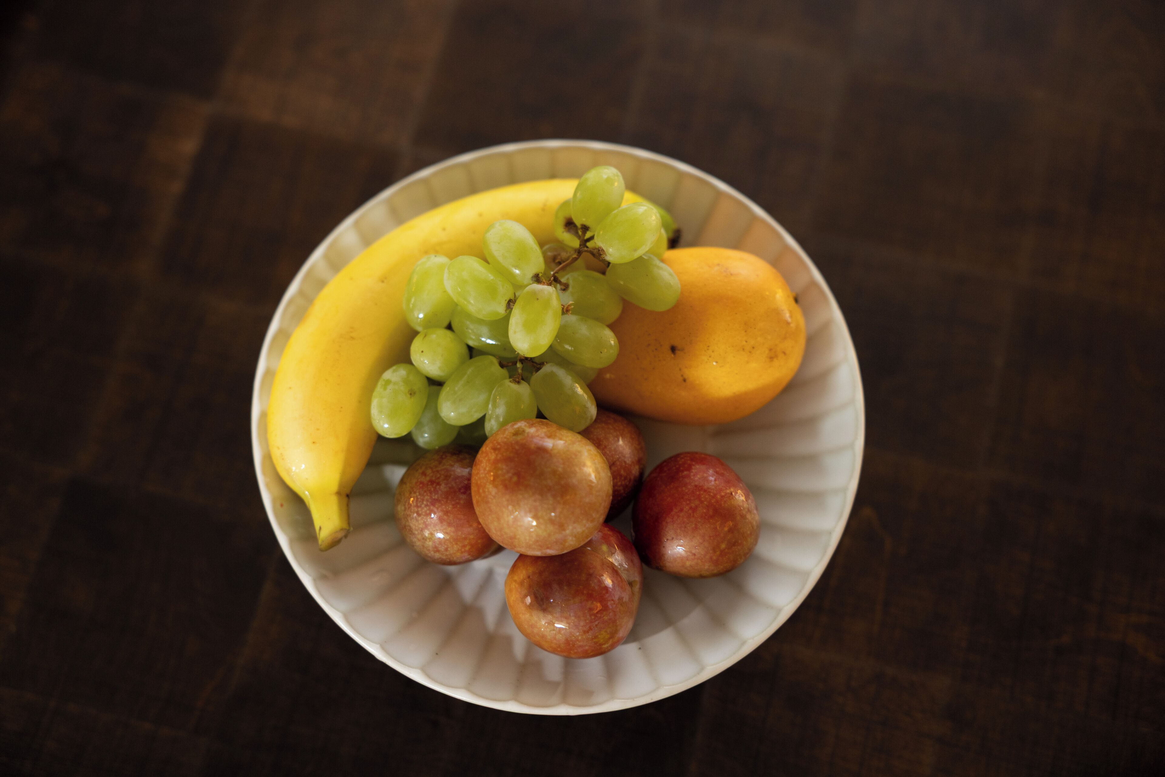 Un plat amb plàtan, raïm i préssecs.