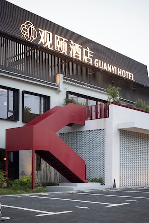 Un hotel con una fachada moderna, una escalera destacada y un cartel que indica el nombre 'GUANYI HOTEL'.