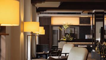 A modern interior with a seating area, a kitchen in the background, and a dining table with chairs.