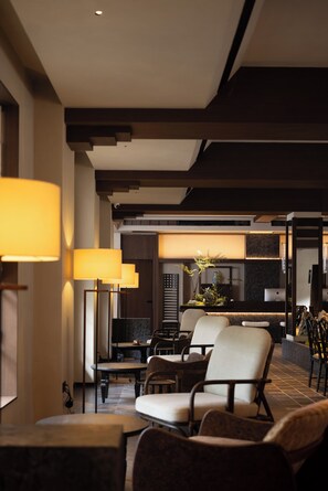 A modern interior with a seating area, a kitchen in the background, and a dining table with chairs.