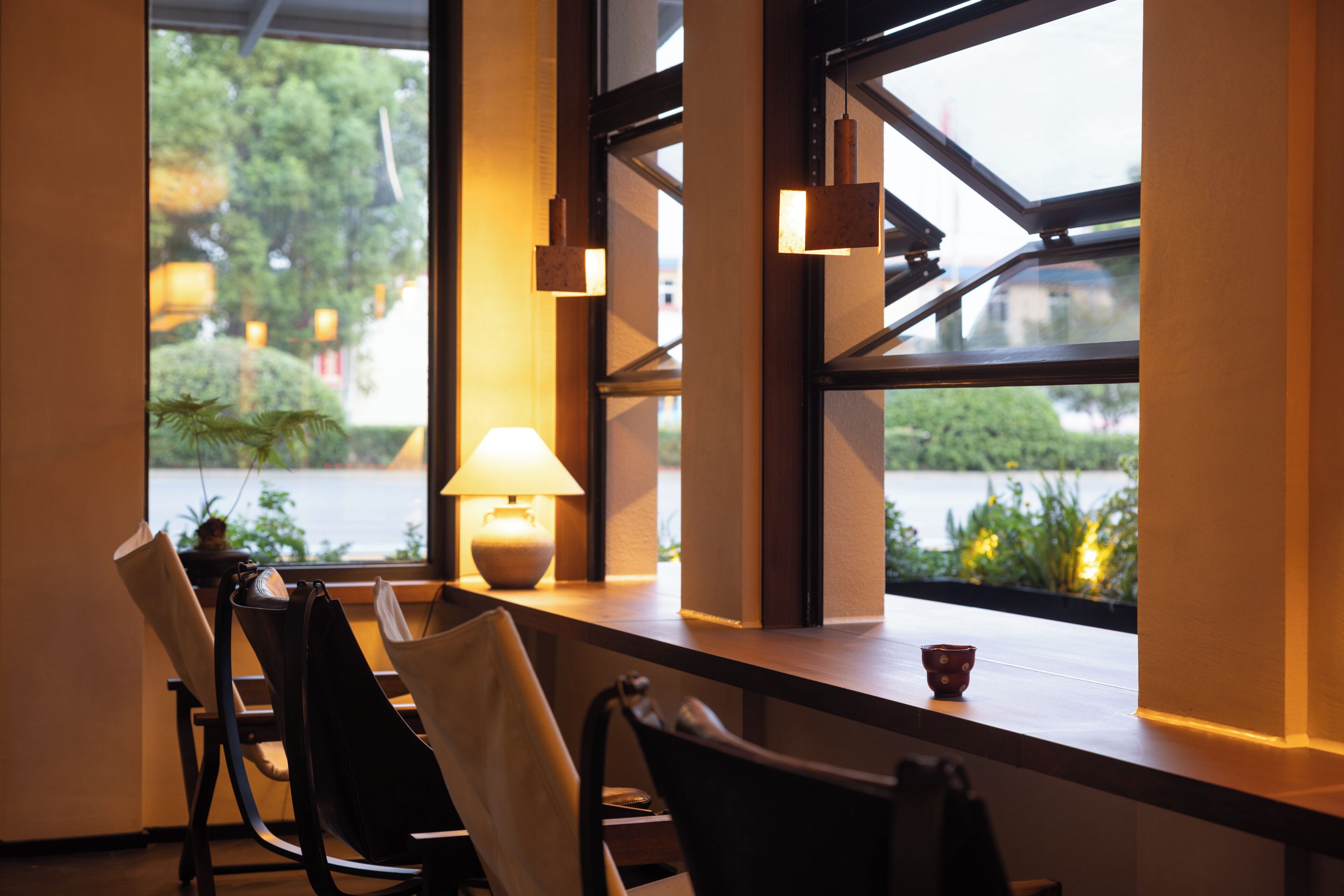 A seating area with chairs and a table, a lamp, and a view of a body of water through large windows.