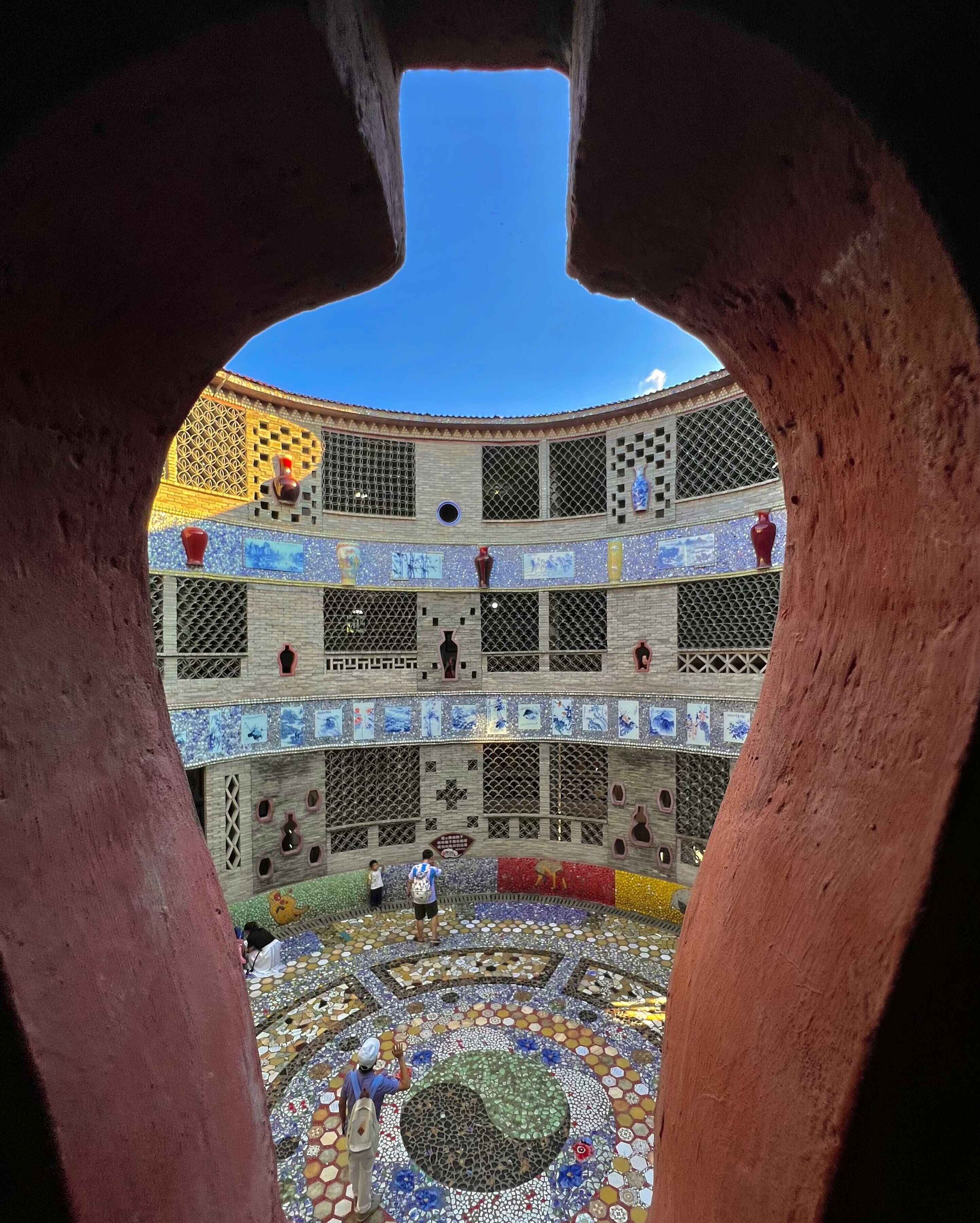 Un patio con suelo de baldosas, una fuente central y un edificio de varios niveles y ventanas.