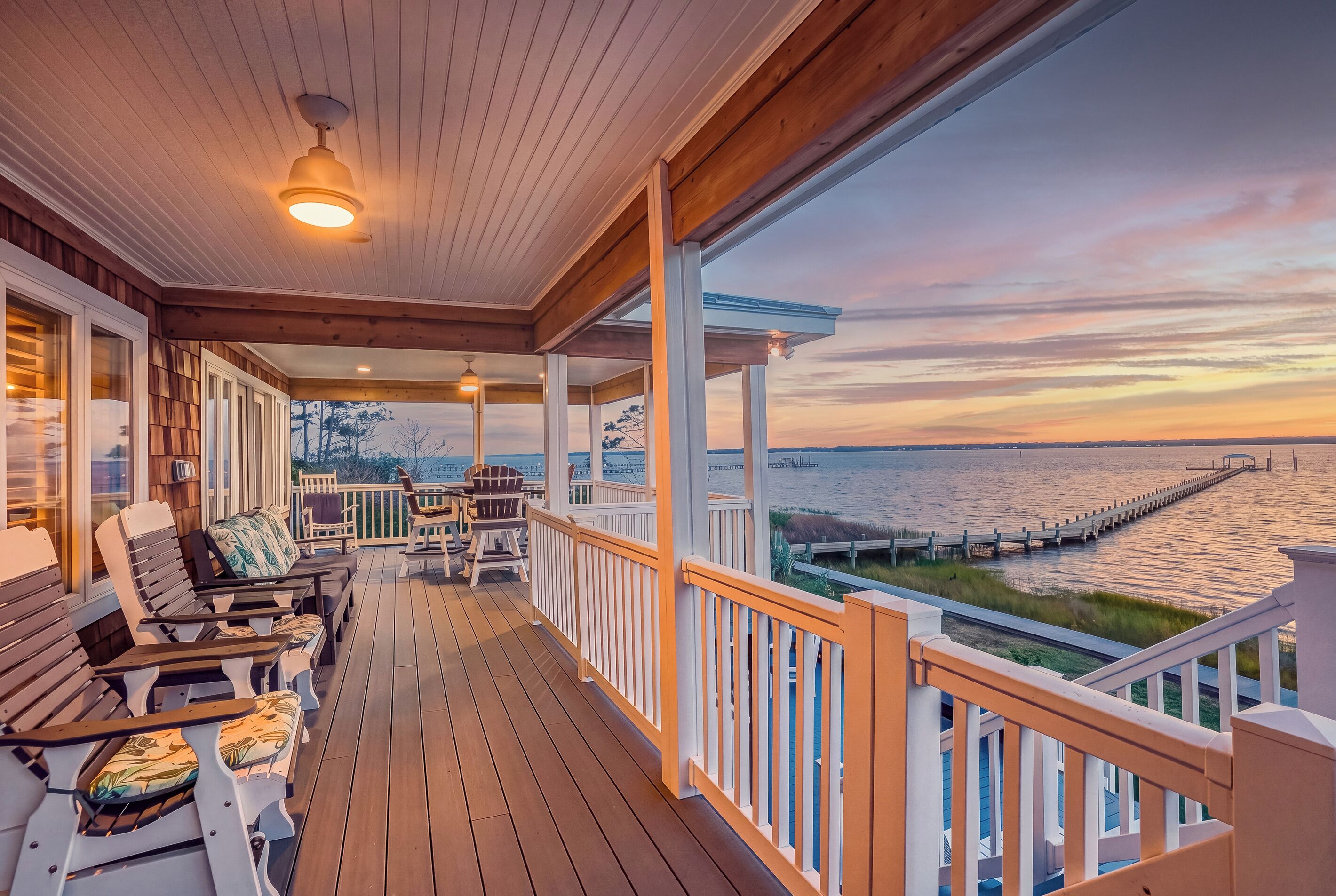 A wooden deck with outdoor seating, a railing, and a view of the water.