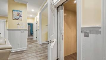 A hallway with white doors, a beige wall, and a wooden floor.