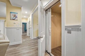 A hallway with white doors, a beige wall, and a wooden floor. - Private Gated Waterfront Estate with Pool, Hot tub, Elevator, Playground & Dock (Morehead City)