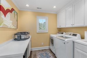 A laundry room with a washing machine, dryer, and a microwave on a countertop. - Private Gated Waterfront Estate with Pool, Hot tub, Elevator, Playground & Dock (Morehead City)