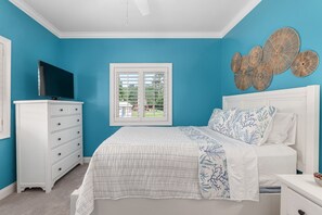 A bedroom with a bed, a dresser, a television, and a window with blinds. - Private Gated Waterfront Estate with Pool, Hot tub, Elevator, Playground & Dock (Morehead City)