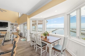 A dining area with a view of the water, wooden flooring, and white furniture. - Private Gated Waterfront Estate with Pool, Hot tub, Elevator, Playground & Dock (Morehead City)