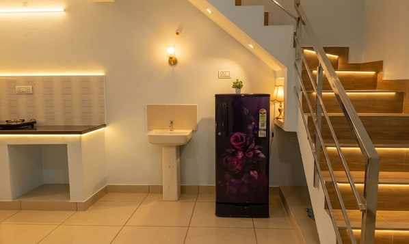 A modern kitchen with a built-in sink, a refrigerator with a floral design, and a staircase with wooden steps.