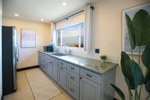 A modern kitchen with a large window, a built-in sink, and a refrigerator.