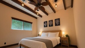 A bedroom with a bed, a ceiling fan, a window, and wall art. - Oceanfront - Island Views - Shoals Beach House (Ventura)