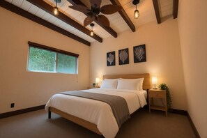 Ein Schlafzimmer mit einem Bett, einem Deckenventilator, einem Fenster und Wandbildern.