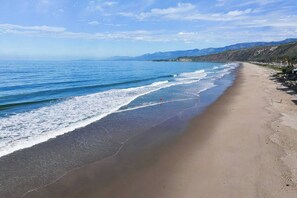 Ein Strand mit freiem Blick auf das Meer und ferne Berge.