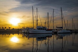 A marina with multiple sailboats docked during sunset.