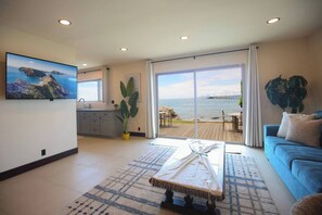 A modern living room with a large window overlooking a deck and the sea.