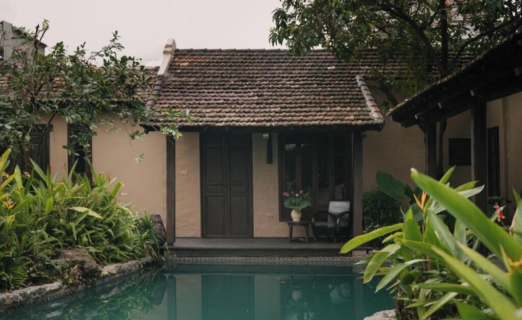 A traditional building with a tiled roof, a pool, and lush greenery.