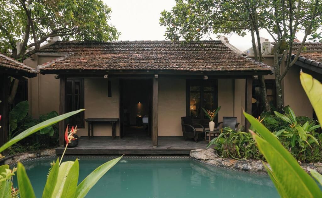 A building with a tiled roof, a pool, and outdoor furniture.