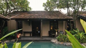 Um edifício com telhado em cerâmica, piscina e mobiliário de exterior.