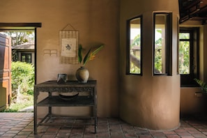 Un interior rústico con una mesa de madera, un florero con una planta y un letrero en la pared.
