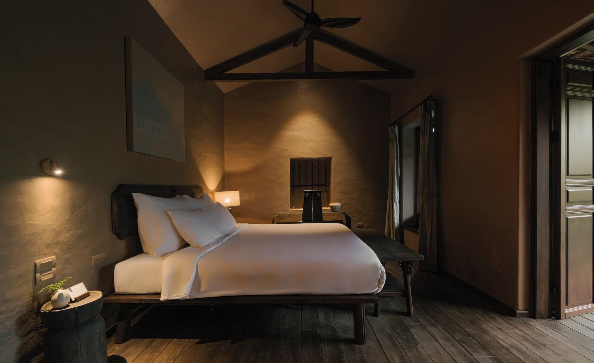 Une chambre à coucher avec un lit, une table de chevet, une lampe et un ventilateur de plafond.