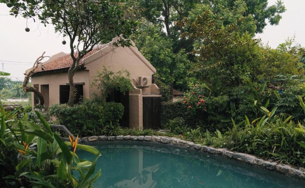 Un edificio con piscina rodeado de abundante vegetación y árboles.
