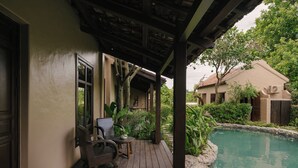 Espaço ao ar livre coberto com piscina, deck de madeira e um edifício com telhado em telhas.