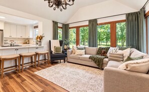 A spacious living room with a sofa, a coffee table, and a dining area with bar stools.
