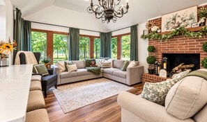 A spacious living room with a sectional sofa, a fireplace, and large windows.