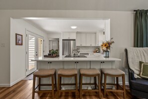 Una cocina moderna con una isla central, taburetes de bar y un refrigerador.