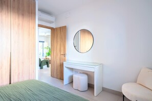 Ein modernes Schlafzimmer mit einem Bett, einem Nachttisch, einem runden Spiegel und einer Tür zu einem anderen Raum.