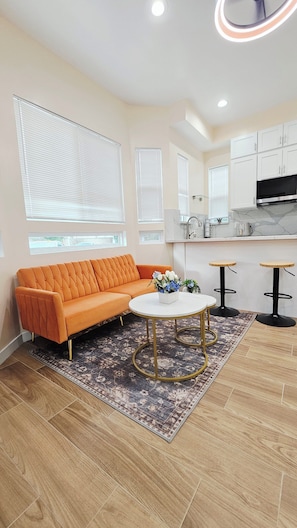 A modern living room with a sofa, coffee table, and two bar stools. - Brand-New Modern 3BR/3BA Private ADU • A/C • High Ceilings • Canoga Park (Los Angeles)