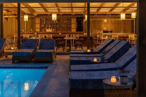 A poolside area with seating, a bar, and a pool. - Skiathos Thalassa (Skiathos)